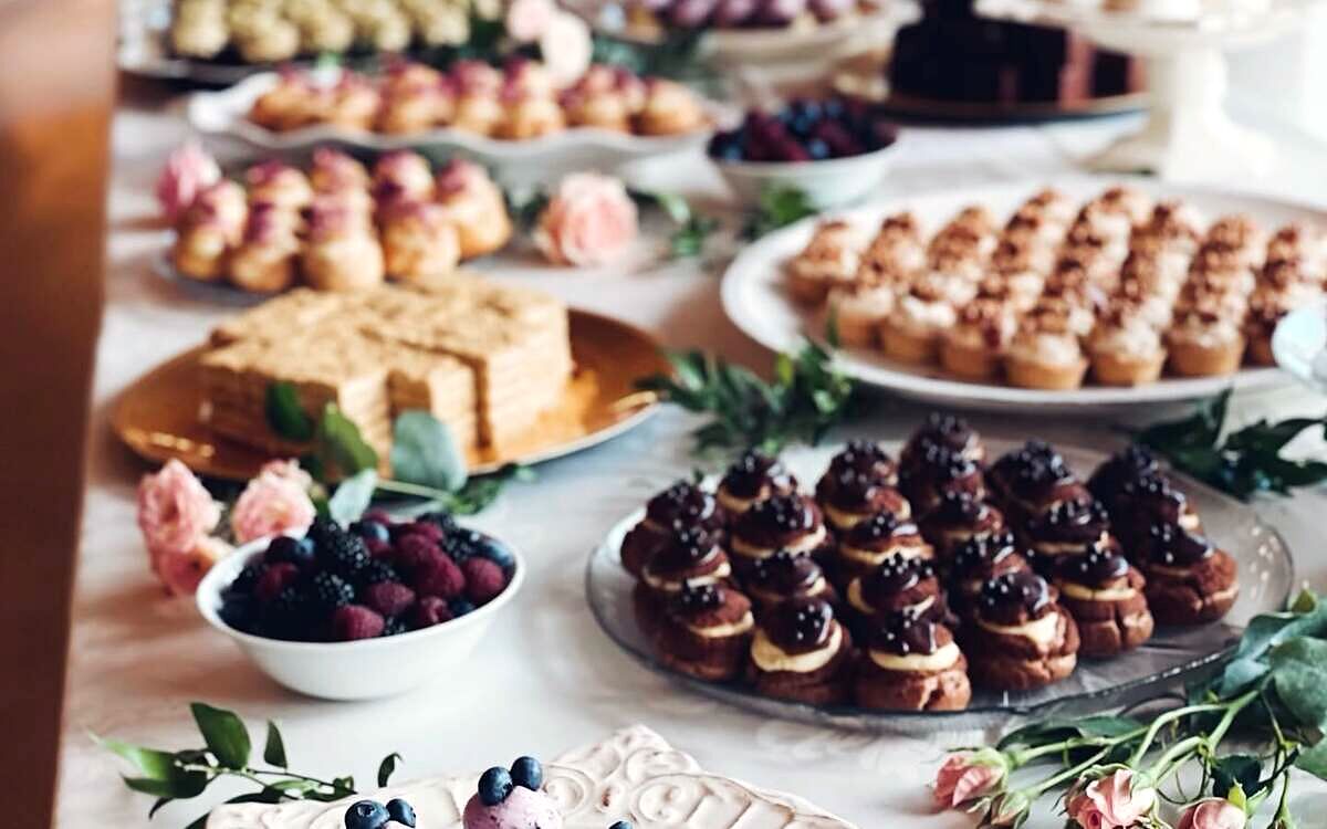 Masă dulce plină cu mignon-uri, tarte și prăjituri mici aranjate pe platouri