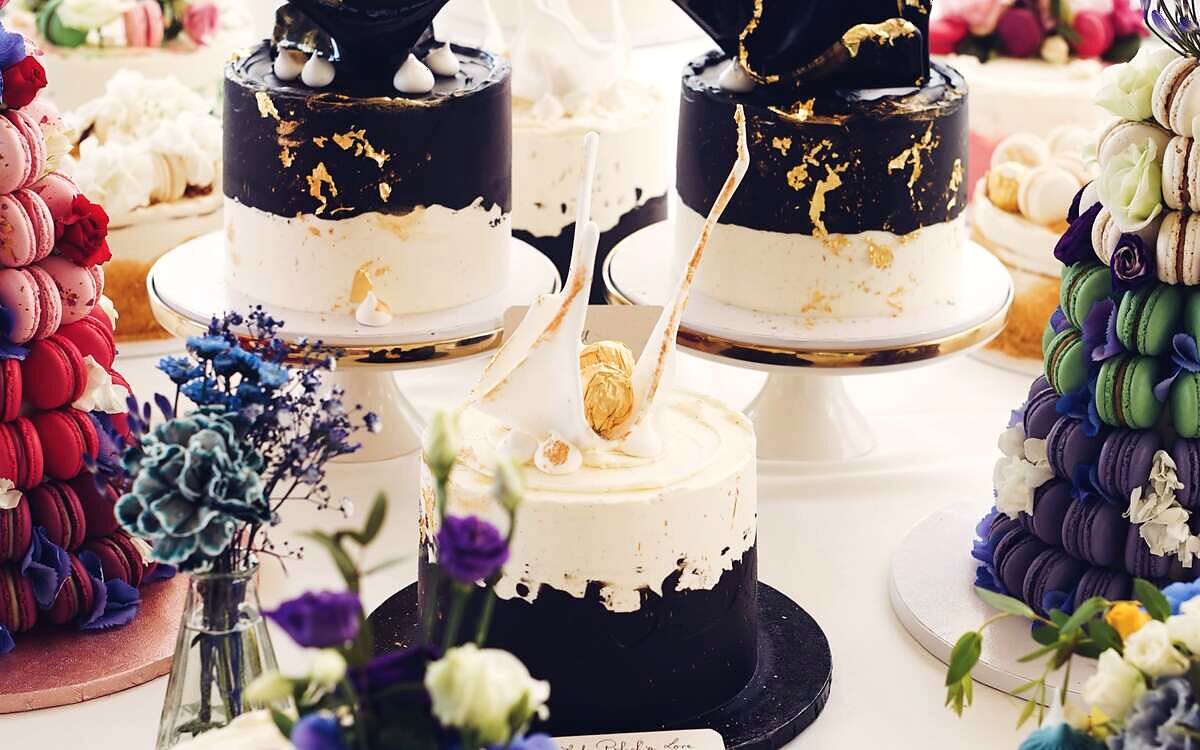 Candy bar cu torturi negre cu accente aurii, turn de macarons și flori de câmp